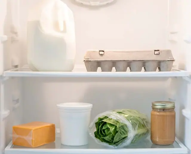 Inside a fridge: milk, eggs, cheddar, yogurt and lettuce